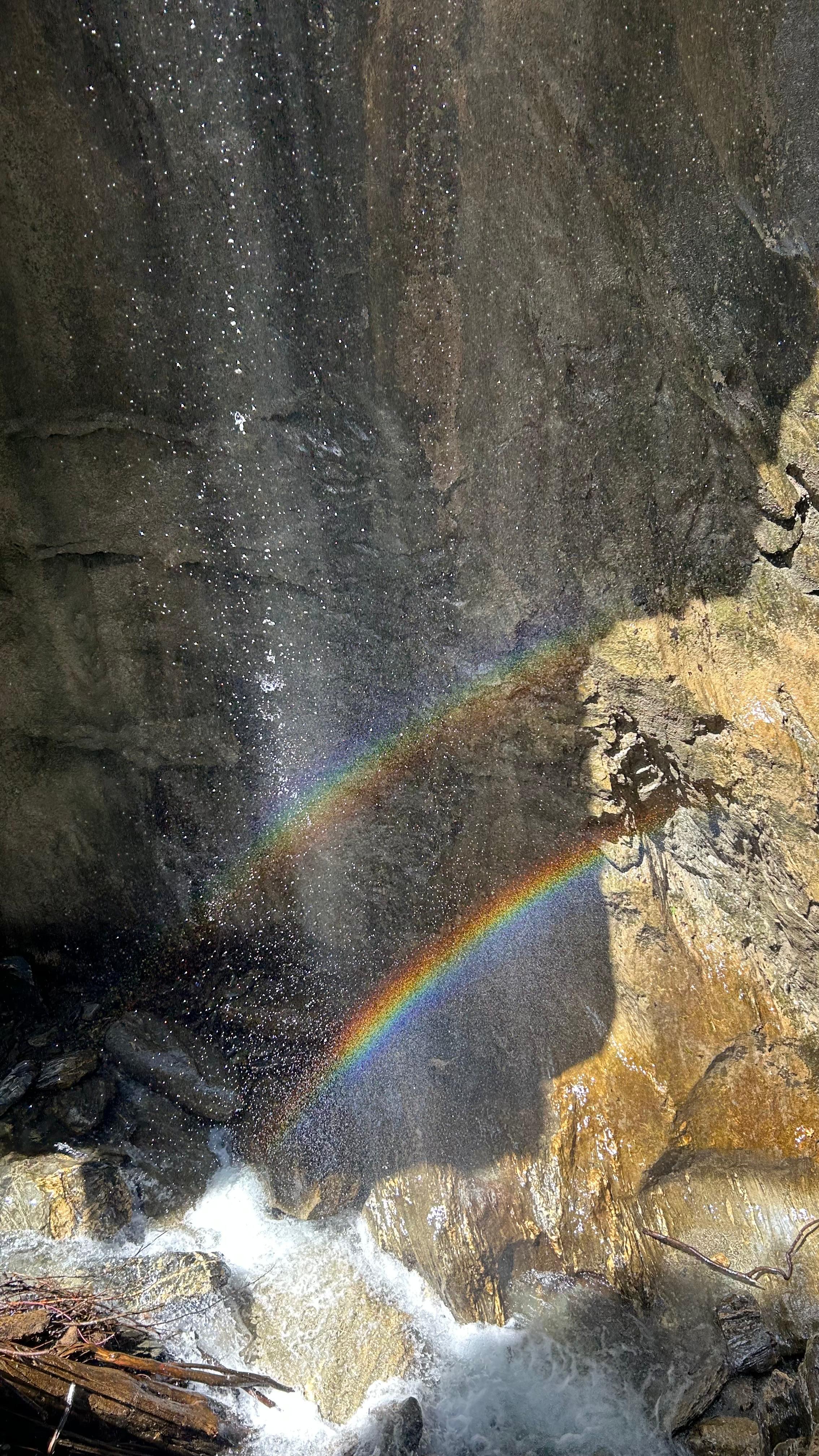 Regenboog in het water naast een rotsachtige waterval